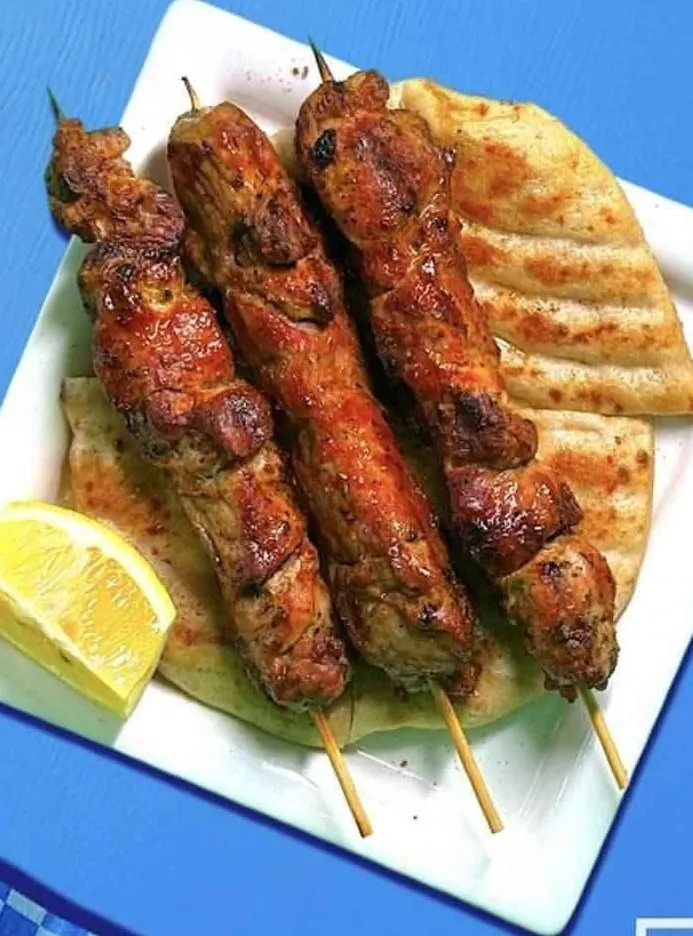 Three souvlaki skewers with pita and lemon
